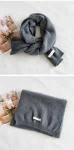 Close-up of dark grey ribbed knit scarf with thick texture and minimalist woven label