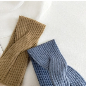 Close-up of ribbed knit knot headbands in khaki and misty blue on a soft white background