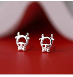 Macro shot of silver hollow calf stud earrings with bow tie on festive red background
