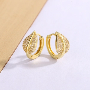 Macro shot of gold leaf earrings with sparkling champagne zircon and detailed texture