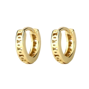 Detail of gold huggie earrings with intricate geometric cutout patterns on white background