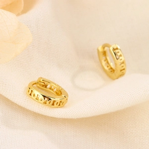 Elegant gold hollow hoop earrings displayed on soft textured fabric background