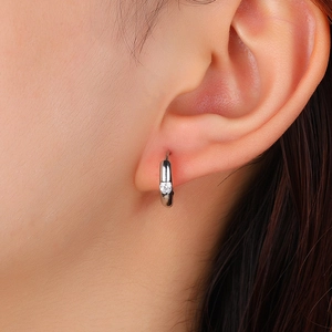 Minimalist silver hoop earring with single zircon inlay on female ear close-up