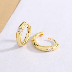 Elegant gold plated hoop earrings with a single round zircon stone on white background