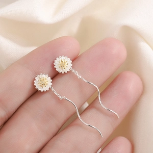 Detail of s925 daisy drop earrings with white petals and gold core on wave chain