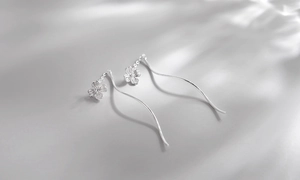 Macro detail of silver petal tassel earrings with elegant long wavy threader chains