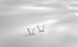 Macro shot of silver heart studs featuring a textured brushed metal finish and clean edges