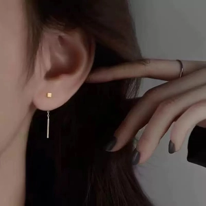 Minimalist gold square stud earrings with sleek long bar pendant on female model