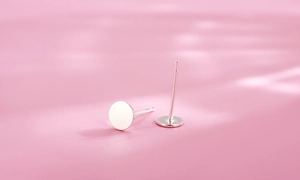 Close-up of minimalist S925 sterling silver flat disk stud earrings with hallmark detail