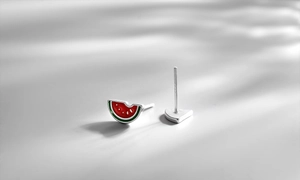Detailed view of handmade watermelon enamel studs with vibrant red and green colors