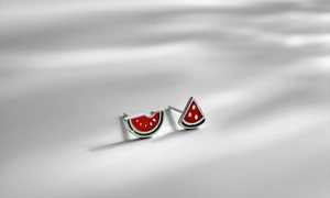 Detailed view of handmade enamel watermelon stud earrings with soft leaf shadows