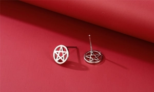 Macro shot of silver cutout pentagram stud earrings on a deep red background