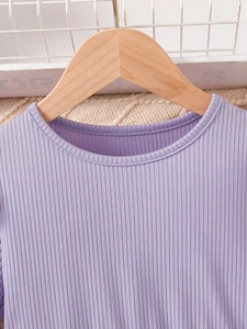 Close-up of a purple ribbed long-sleeved dress for girls on a wooden hanger quality.