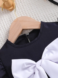 Zwarte zomerjurk voor meisjes met een grote witte strik op een houten hanger