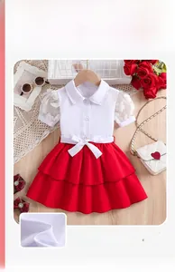 Détail de chemise blanche à manches bouffantes en dentelle et jupe rouge pour filles