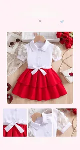 Détail d'une chemise fille en dentelle blanche et jupe plissée rouge avec nœud décoratif