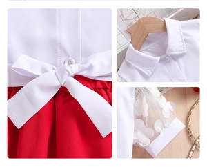 Détail de chemise blanche fille avec manches en tulle, papillons 3D et jupe plissée rouge