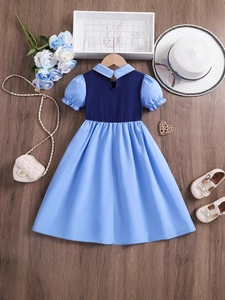 Mädchen Patchwork-Kleid in Blau mit Puffärmeln und A-Linien-Rock auf Holzgrund