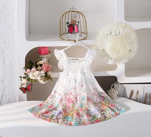 Detalle de vestido floral de niña con tirantes de volantes y sombrero de paja a juego