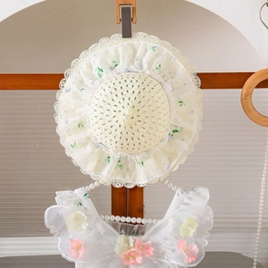 Detalle de sombrero de paja para bebé con flores 3D y vestido floral de encaje