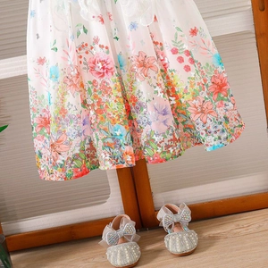 Detalle de vestido de gasa floral con zapatos plateados con lazo de perlas