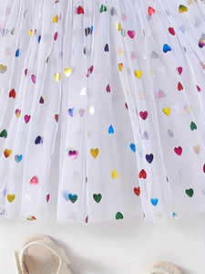 Detail of white tulle skirt featuring colorful heart sequins and mesh layering