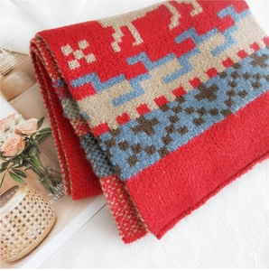 Close-up detail of knitted winter scarf with red and khaki geometric reindeer pattern