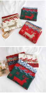 Detail of Christmas reindeer knit scarf with red and green Nordic patterns on white cloth