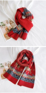 Detail of red knitted scarf with beige elk pattern and winter holiday geometric motifs