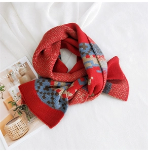Detailed knit texture of a red and blue geometric pattern wool scarf with soft fringe