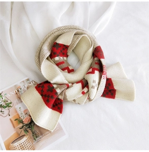 Detail of winter knit scarf with festive red and brown plaid patterns on creamy white base