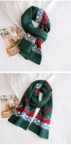 Detail of dark green knitted Christmas scarf with Nordic pattern on white background