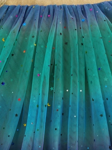 Detail of girls rainbow tulle tutu with colorful star and moon sequins and gold waistband
