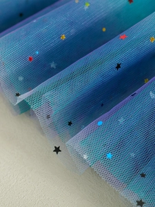 Detail of gradient rainbow mesh fabric with colorful star sequins for tutus