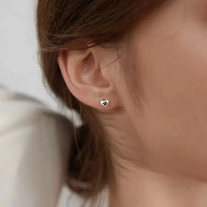 Polished heart-shaped stud earrings for women shown on ear in minimalist style