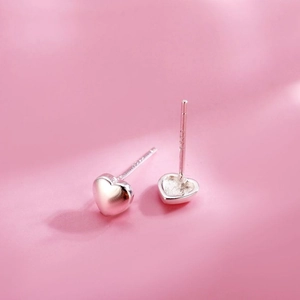 Polished S925 sterling silver heart stud earrings for women on a pink background