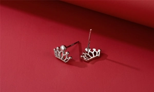 Macro detail of S925 sterling silver crown studs showing the hallmark on minimalist red background