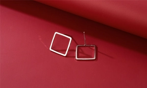 Detail of square geometric silver stud earrings with polished hollow structure