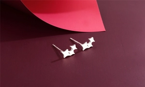 Detail of S925 sterling silver wing earrings on elegant deep red background