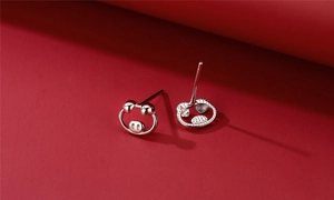 Macro shot of cute pig-shaped S925 sterling silver stud earrings on a vibrant red background
