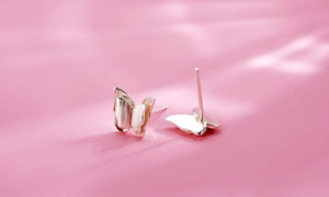 Macro shot of silver butterfly stud earrings featuring a textured brushed metal finish