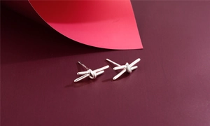 Close-up of S925 sterling silver knot stud earrings with polished finish on red surface