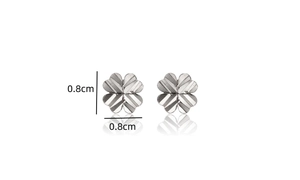 Macro detail of silver four-leaf clover stud earring with diagonal striped texture