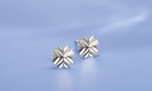 Detail view of silver clover stud earrings featuring a textured radial brushed metal finish