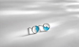 Detailed view of silver round studs featuring sky blue wave pattern and enamel finish