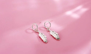 Dettaglio degli orecchini a foglia traforata in argento sterling S925 su fondo rosa
