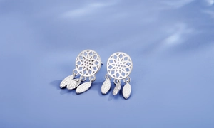 Detailed view of silver dreamcatcher earrings with feathers against blue water ripples