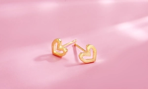 Close-up of heart-shaped hollow earrings in gold finish with a matte texture