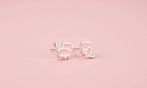 Gros plan de boucles d'oreilles chat roses avec base en argent sur fond rose
