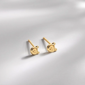 Polished golden s925 silver teddy bear stud earrings on a light gray surface